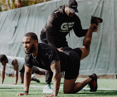 A sports performance coach guides an athlete through a lower-body exercise