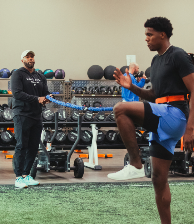 A coach guides an athlete through conditioning drills using a weighted rope.