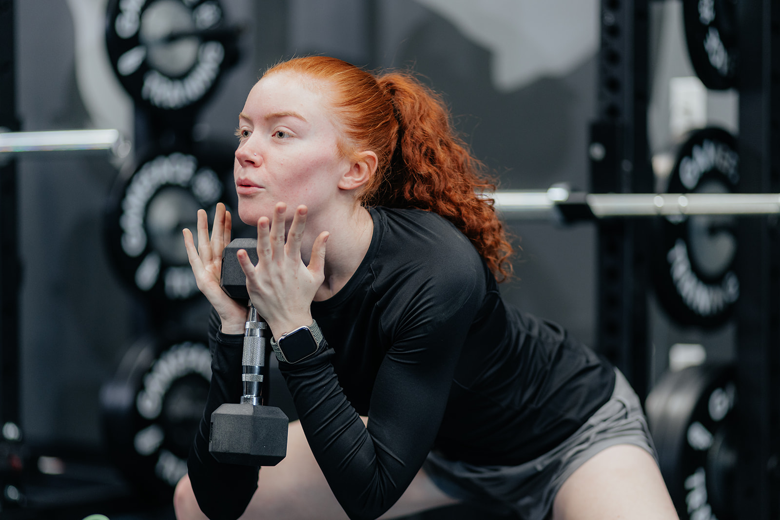 A female athlete in a lunge position doing a drill with a dumbbell.
