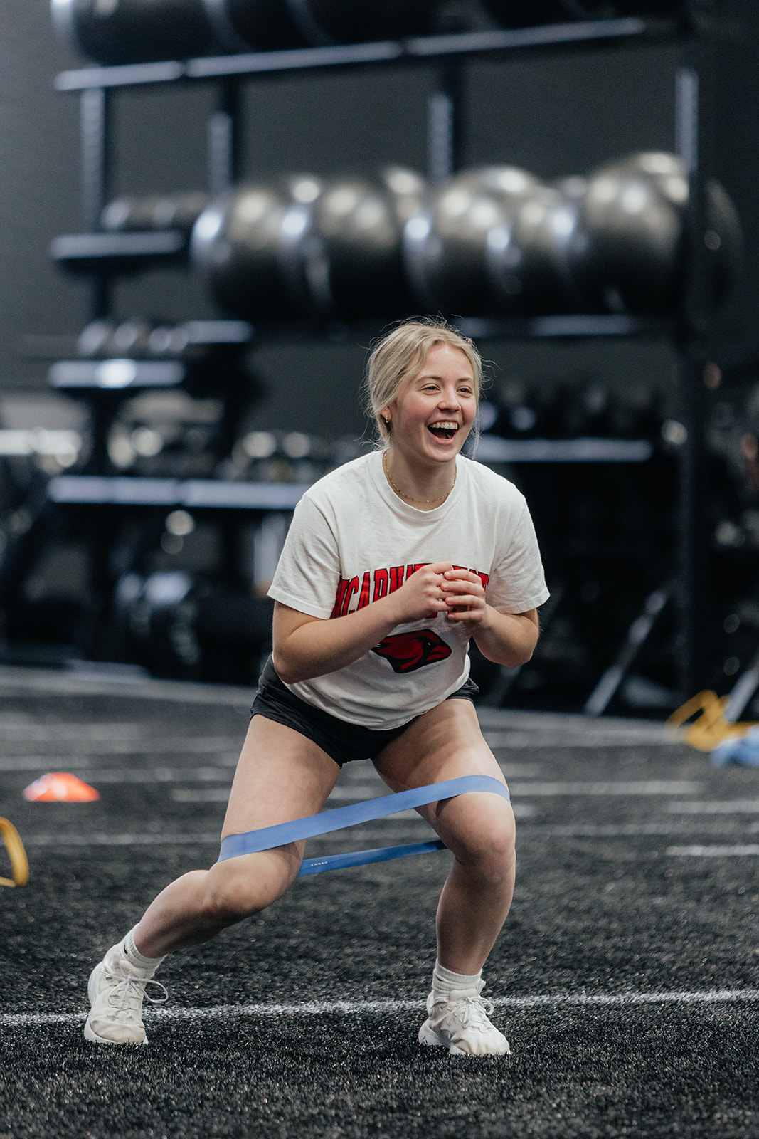 An athlete is smiling while doing a band drill on turf.
