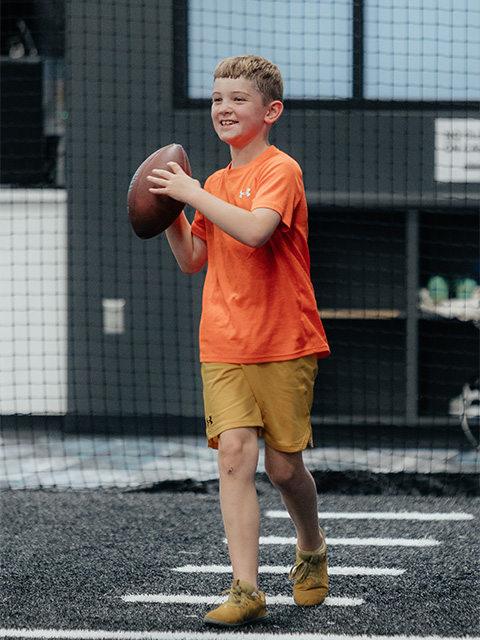A young boy smiles as he prepares to throw a football.