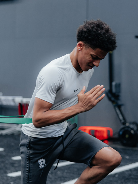 An athlete sprints while wearing resistance equipment.