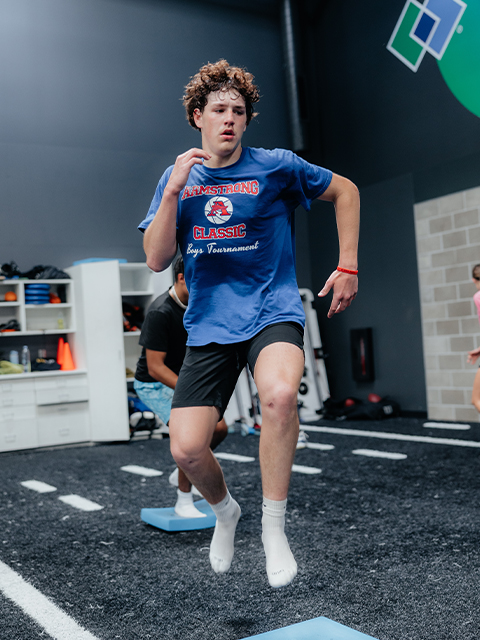 An athlete performs jumping drills on the turf.